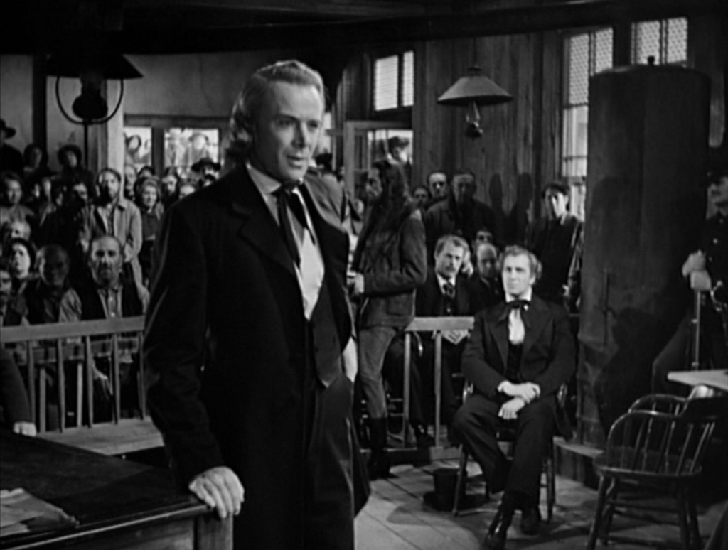 Brigham Young stands in front of the jury to defend Joseph Smith (Vincent Price in the background).